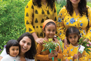 Three women and thee children in yellow dresses smiling