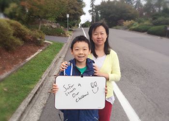 image of mom and son standing on street with placard